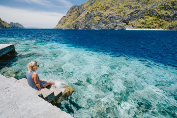 El Nido, Palawan, Philippines. Tourist female on Matinloc dock pier enjoying tapiutan strait on island tour C