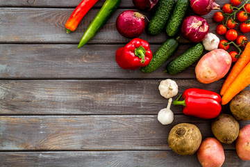 Set of autumn vegetables - potato, cucumber, carrot, greenery - on dark wooden background top-down copy space frame