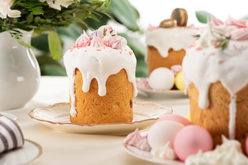 Selective focus of Easter cakes with white glaze and meringue on table