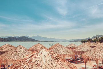 Abstract view of amazing beach landscape with straw umbrella near azure Aegean sea. Mediterranean...