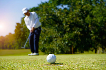 Blurred golfer playing golf in the evening golf course, on sun set evening time.