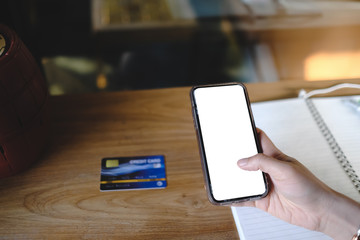 Close up of woman using cell phone with credit card sending massages and shoping online on the coffee shop with black screen,texting,video calls.