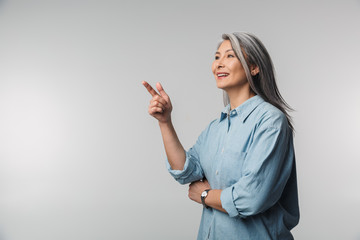 Image of adult mature woman pointing finger aside at empty space