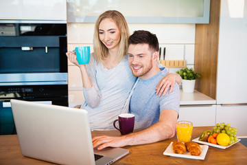 young happy couple having breakfast at home