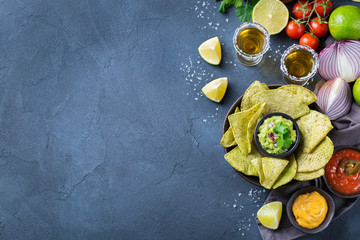 Obraz na płótnie Canvas Corn tortilla chips nachos with guacamole, chili, cheese salsa, tequila