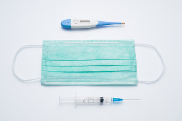 Medical mask, thermometer and syringe on gray background