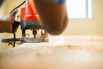 Carpenter drills a hole with an electrical drill,Young man worker in the carpenter workroom.