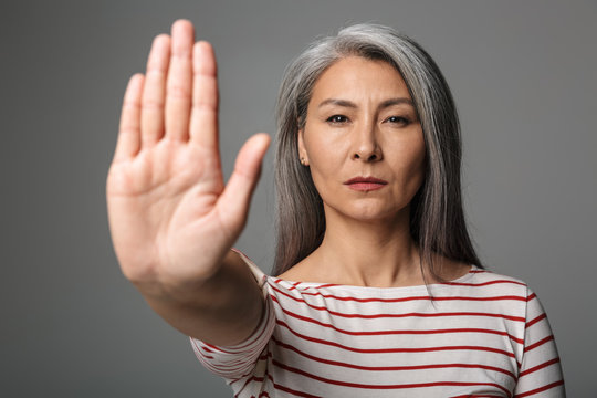 Image of adult woman wearing striped shirt doing stop or denial gesture