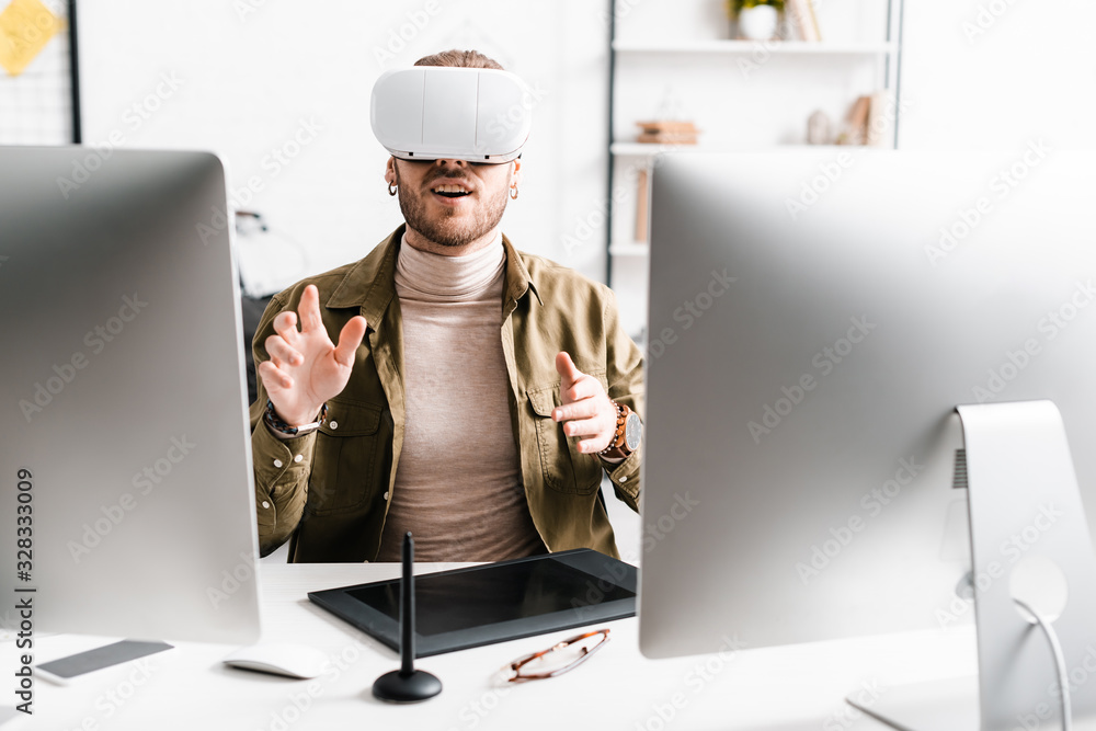 Aufkleber excited 3d artist in virtual reality headset gesturing near computers and graphics tablet on table