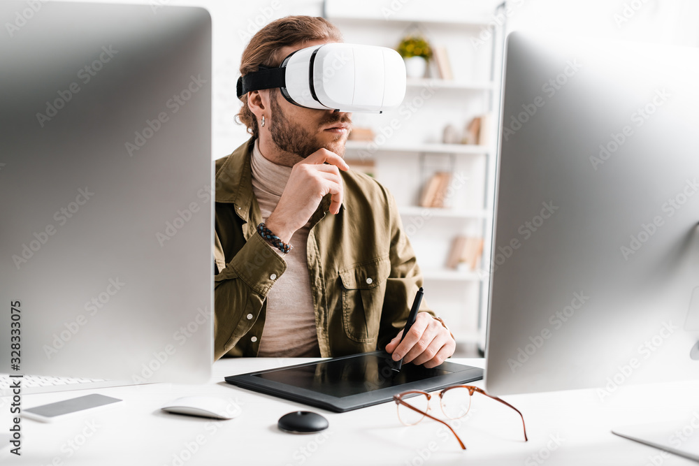 Poster selective focus of 3d artist using virtual reality headset and graphics tablet near computers on tab