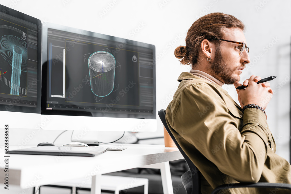 Poster side view of 3d artist holding stylus of graphics tablet and looking away near project of 3d design 