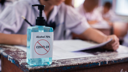 Alcohol 70%  Sanitizer standing on the table for protect corona virus or covid-19 with students doing exam  in classroom of school with stress.16:9 style