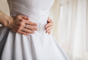 Obraz na płótnie Canvas Bride in white dress with golden ring adjust her dress