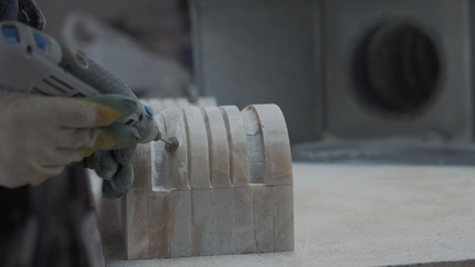 Engraver processes the surface of a marble plate using electric tools	