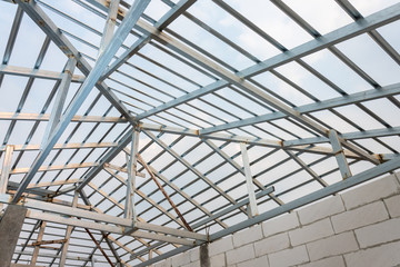 Obraz premium Structure of steel roof frame for home construction. Concept of residential building under construction.