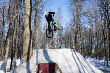 Mtb rider cycling in winter dirt jumping. An athlete in a helmet does a trick on a bicycle in snowy...