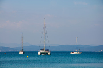 Fototapeta premium Two sailing boats and one catamaran at anchor in front of French coast.