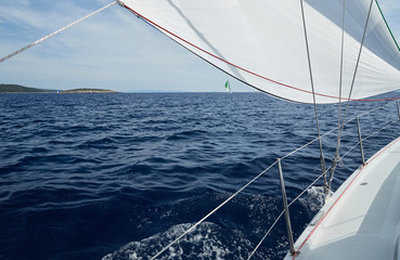 The sailboat goes on sails, a view of the sea and other sailboats through a sail and ropes