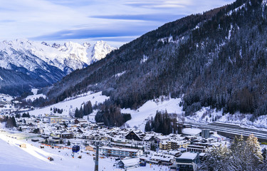 Sankt Anton, Austria - December 28, 2019 - the ski resort town of St. Anton am Arlberg, Austria with amazing afternoon winter sky and snowy mountains covered with pine trees in the background