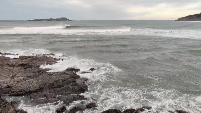surfers in left wave of mundaka, in basque country