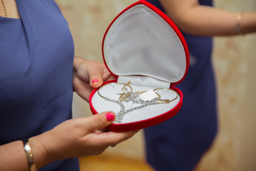 At the wedding the bride is given a heart-shaped gold necklace. The woman was holding gold in a red box.