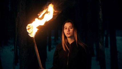 Young beautiful woman with torch in night forest - obrazy, fototapety, plakaty