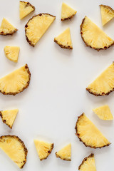 Bright flat lay with pineapple slices on a white background and a copy space in the middle