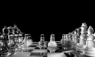 Glass or crystal chess set with opposing pawn pieses isolated on black background with copy space. Battle, strategy, planning or business concept.