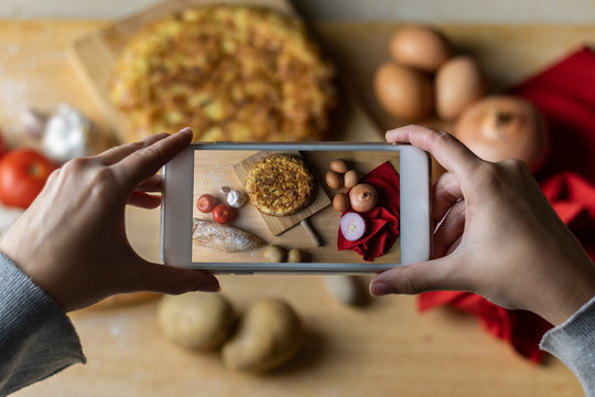  Woman holding phone taking picture of spanish potato omelette