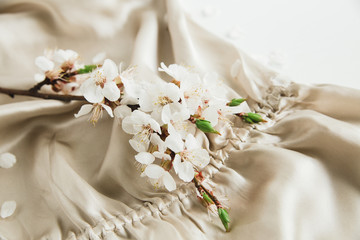 Obraz na płótnie Canvas White blossom flowers on the beige silk fabric cloth.Elegant feminine style.White backdrop.