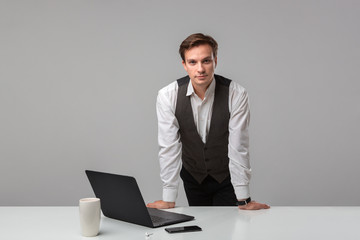 Businessman in a white t-shirt and grey vest working on a laptop