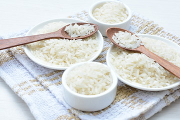 Natural raw white rice grains, on display in bowl and wooden spoon