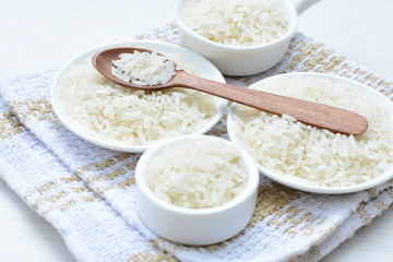 Natural raw white rice grains, on display in bowl and wooden spoon