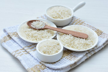 Natural raw white rice grains, on display in bowl and wooden spoon