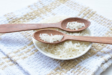Natural raw white rice grains, on display in bowl and wooden spoon