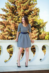 Full-length portrait of a young brunette woman in dress posing summer street