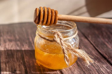 honey in a glass jar on a wooden background