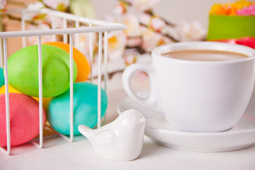 A cup of tea, small spring cake, flowers sakura, colorful eggs for Easter day. Spring concept.