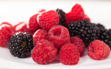 handful of raspberry and blackberry berries on white background