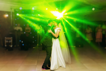 The first wedding dance of the newlyweds..Romantic atmosphere. Light floodlights in the hall.