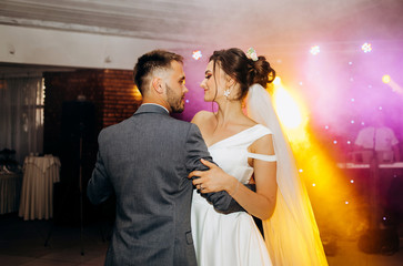 The first wedding dance of the newlyweds..Romantic atmosphere. Light floodlights in the hall.