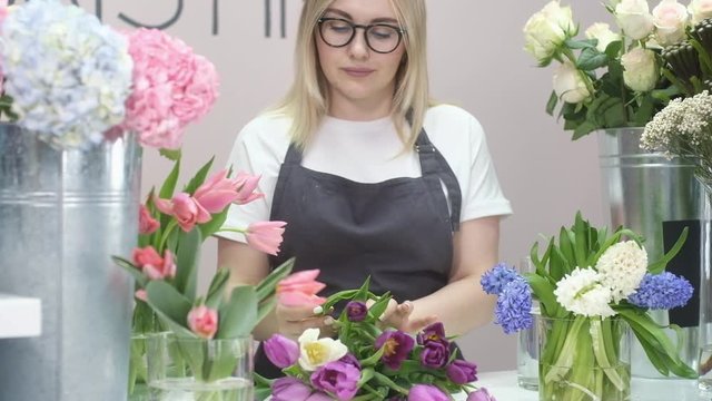 Floristic workshop. A young Woman makes a bouquet of fresh tulips . sale of plants in the store. Flower shop as a small business and hobby.