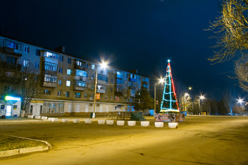 Christmas tree on the snowless square of the night city. Zaporizhzhya region, Ukraine. January 2014