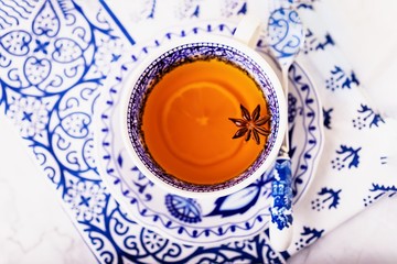 A cup of lemon tea with anise star. White and blue dishes