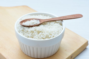 Natural raw white rice grains, on display in bowl and wooden spoon