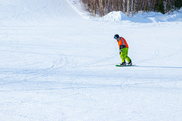 A snowboarder in colored clothes on a snowboard has rolled down the side of a mountain.
