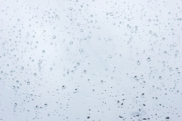 raindrops on glass, closeup, texture of water droplets with a blue tint