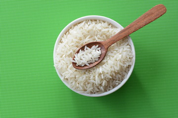Natural raw white rice grains, on display in bowl and wooden spoon