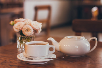 Beautiful fresh roses near a cup of tea and a in pastel tones romantic mood