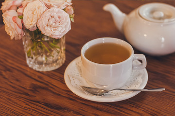 Beautiful fresh roses near a cup of tea and a in pastel tones romantic mood